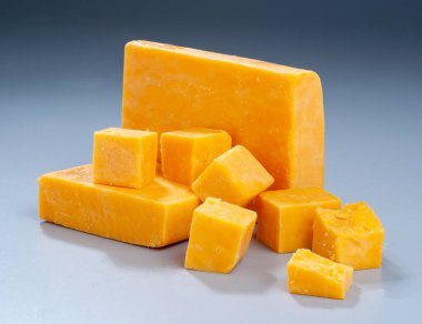 Gradent Arkaplan Üzerine Kırmızı Cheddar Peynir ve Küp - Mutfak ve Gurme Kullanımı İçin Mükemmel. Canlı bir kırmızı çedar peyniri gösterisi, sert bir blok ve düzgün kesilmiş küplerle.. 