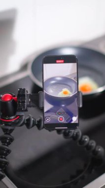 Bir yemek pişirme dersi, akıllı telefon süreci yukarıdan çekerken tavada yumurta kızartmayı gösterir. Bu düzenek, adımları takip etmeyi kolaylaştırıyor..