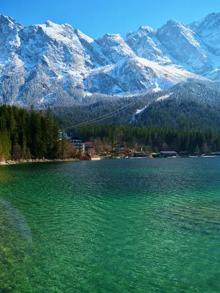 Turkuaz sular, berrak mavi gökyüzünün altındaki görkemli karlı tepeleri yansıtır. Bereketli ormanlar kıyıya sarılıyor, sakin bir manzara yaratıyor doğa severler için mükemmel..