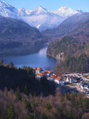 Yükselen dağların arasına yerleşmiş göller boyunca büyüleyici bir köy görülebilir. Karla kaplı zirveler, berrak kış gökyüzünü yansıtarak, sakin bir atmosfer yaratır..