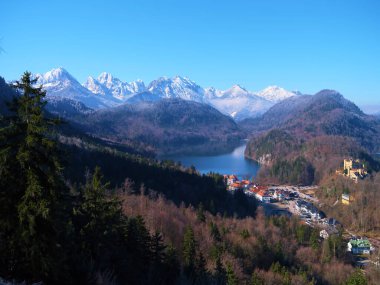 Huzurlu bir gölü çevreleyen görkemli dağlar, ağaçların arasına yerleştirilmiş pitoresk bir şato. Bu Bavyera manzarası aydınlık ve aydınlık bir günde doğanın güzelliğini sergiliyor..