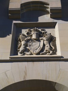 Süslü taş oymacılığı, her iki tarafında aslanlar olan bir arma sergiliyor. Dış taraftaki görkemli binalarda, güneş ışığıyla aydınlatılıyor..