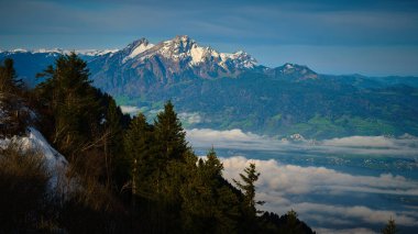 Görkemli dağlar ufuk boyunca uzanır, yemyeşil vadiler ve aşağıdaki bulutlarla çevrili, İsviçre 'de açık bir günde yakalanır. Doğanın ihtişamı tam gösterimde..