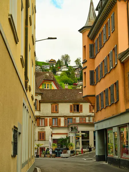 Dar bir cadde, tepenin kenarındaki büyüleyici ve renkli evleri gözler önüne sermek için açılıyor. Parlak güneş ışığı, eşsiz mimari ve yeşilliği gözler önüne sererek sahneyi aydınlatıyor..
