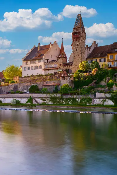 Sakin bir nehrin yanında kendine özgü kuleleri olan antik bir şatonun manzarası. Güneş, yapıyı çevreleyen büyüleyici mimari ve yeşilliği güçlendiren sıcak bir parıltı yayar..