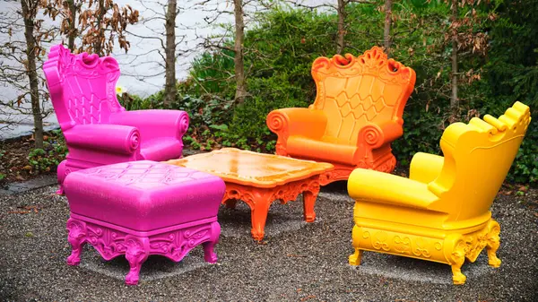 Renkli sandalyeler ve pembe, turuncu ve sarı renkli koltuklar canlı bir açık hava ortamında dekoratif bir masanın etrafına dizilerek bahçelerin neşeli atmosferini arttırır..