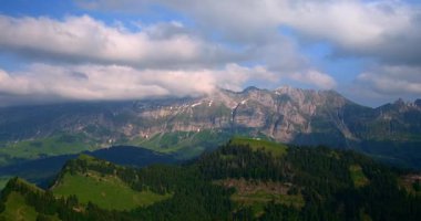 Görkemli dağların, yeşil tepelerin ve açık mavi gökyüzünün altında sürüklenen bulutların bulunduğu İsviçre Alpleri 'nin nefes kesici manzarasını deneyin. Doğanın güzelliği her yere yayılır..