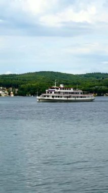 Canlı yeşil tepelerle çevrili, dingin sularda büyük bir yolcu gemisi süzülüyor. Yakınlarda, bulutlu bir gökyüzünün altında kıyı şeridi boyunca uzanan tuhaf bir kasaba var..