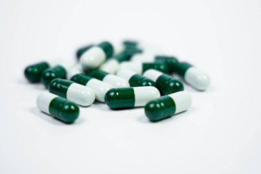 Beyaz arka planda izole edilmiş antibiyotik kapsüllerinin detaylı bir fotoğrafı. Sağlık kampanyalarında enfeksiyon tedavisi ve tıbbi bakım için mükemmel bir örnek. beyaz ve yeşil kapsüller.