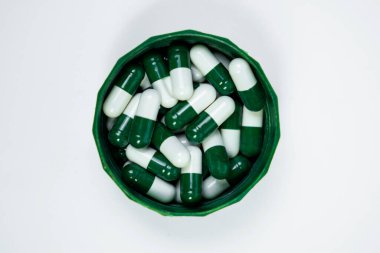 Beyaz arka planda izole edilmiş bir grup beyaz ve yeşil kapsül. İlaç ambalajı tasarımı ve ilave reklamlar için mükemmel..