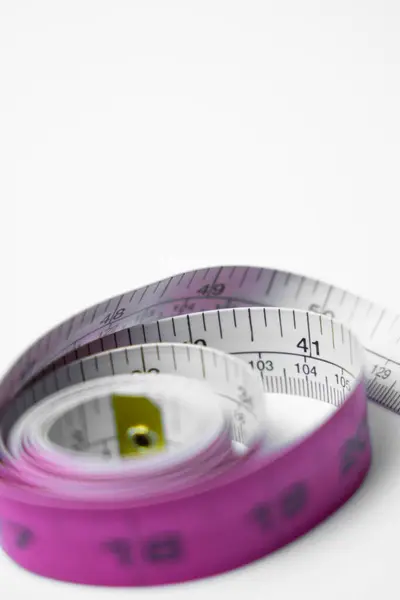 Temiz beyaz bir arkaplanda parmak ve santimetre işaretlerini gösteren bir mezuranın detaylı yakın plan çekimi. İnşaat, DIY projeleri ve eğitim içeriği için mükemmel.