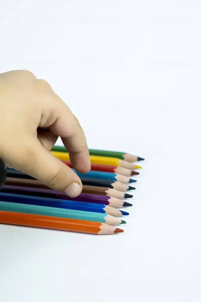 Beyaz arka planda izole edilmiş renkli kalemlerle sanat araştıran bir çocuğun canlı fotoğrafı. Eğitim blogları ve yaratıcı reklamlar için harika..