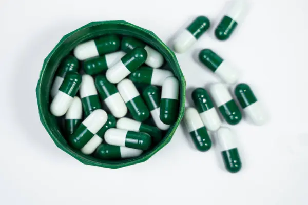 İlaç kapsüllerinin, multivitamin kapsüllerinin yüksek kaliteli bir fotoğrafı ve beyaz arka planda sergileniyor. İlaç reklamları için idealdir..