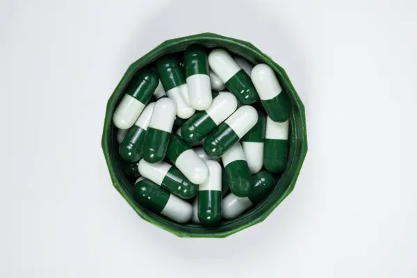 Beyaz arka planda izole edilmiş bir grup beyaz ve yeşil kapsül. İlaç ambalajı tasarımı ve ilave reklamlar için mükemmel..