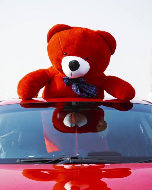 Big Teddy bear in a red beautiful car for the loved one  clipart