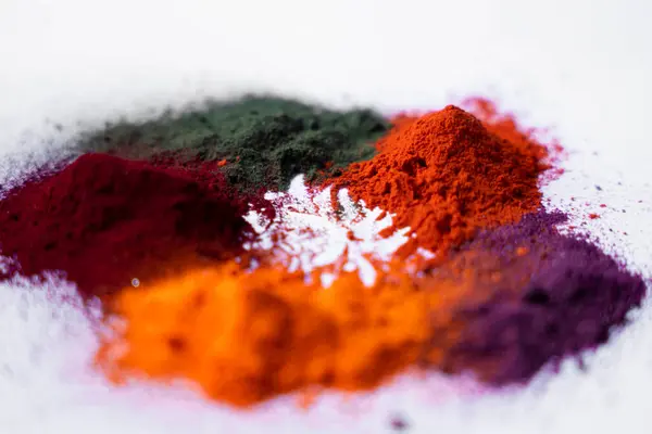 Temiz beyaz zemin üzerinde canlı Holi festival renkleri (turuncu, kestane rengi, yeşil, sarı ve mor) detaylı bir yakın plan. Renklerin dokularını ve zenginliğini göstermek için mükemmel.