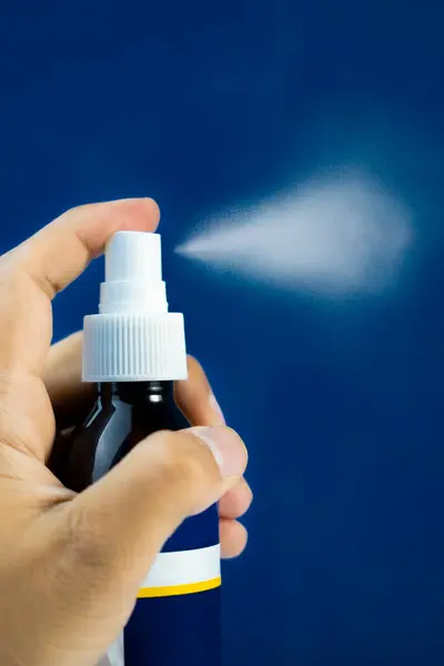 Mavi arka planda izole edilmiş, su sisi efektli saç spreyi şişesi modeli. Ürün gösterileri için harika..