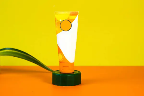 Yellow and orange sunblock with props, set on a matching background.