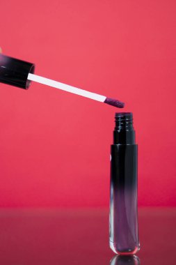 Pembe dudak parlatıcısı, pembe arka planda izole edilmiş. Güzellik ürünleri ve pazarlama için ideal.