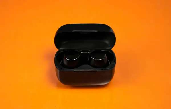 Kablosuz kulaklıklar turuncu arka planda, teknoloji markalaşması ve ürün sunumları için mükemmel.