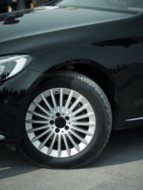 Gösterişli gümüş alaşımlı jantlı şık bir siyah araba tekerleği lüks araç reklamları ve otomotiv ürünleri vitrinleri için ideal. Premium tasarım ve performansı vurgulamak için harika.