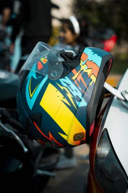 Cesur, renkli bir kask şık bir spor bisikletinin üzerinde öylesine asılı duruyor, sürücü kişiliği ve makine saldırganlığı arasında çarpıcı bir kontrast oluşturuyor. Yaşam tarzı markalaşması, vites yükseltme ya da motor sporu sosyal içeriği için mükemmel..