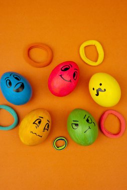 Bir grup Paskalya yumurtası, turuncu bir arka plana yerleştirilmiş şirin emoji yüzleri ile boyanmış.