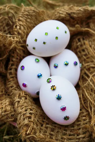 Güzel dizilmiş Paskalya yumurtaları pembe bir kâse ve jüt ambalajında çiçek pulu desenleri olan doğal bir ortamda çekilmiş.                  