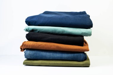 Mavi, yeşil, turuncu ve siyah pantolonlar güzelce katlanmış. beyaz arkaplanda izole