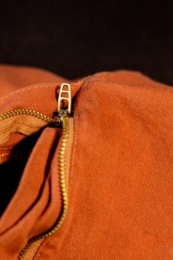 Siyah arka planı olan bir kot pantolonun fermuarının yüksek kaliteli yakın çekimi işlevselliğini ve tasarımını gözler önüne seriyor. Moda pazarlaması ya da ürün detay sayfaları için mükemmel.