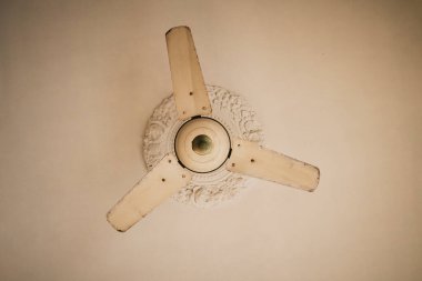 Basit, sade beyaz bıçakları olan eski bir beyaz tavan vantilatörü, onun asgari, yaşlanmış görünümü ve klasik ev tasarımı