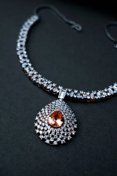 Zengin, siyah bir zemin üzerinde sergilenen göz kamaştırıcı bir beyaz mücevher kolye lüks ve karmaşık işçiliğini vurguluyor. Üst düzey moda, mücevher katalogları ve lüks ürün görselleri için ideal.