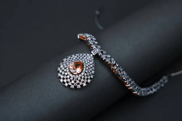 Göz kamaştırıcı beyaz taşlardan yapılmış zarif bir kolye dramatik bir siyah arkaplan üzerine şekillendirilmiş, moda veya ürün gösterim amaçları için kontrastı ve detayı vurguluyor.
