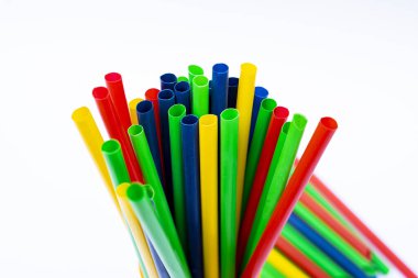 Beyaz arka plan üzerinde sarı bir fincanda canlı plastik pipetlerin yakın plan görüntüsü.