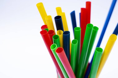 Beyaz stüdyo arka planında sarı bir fincanda çok renkli içki pipetlerinin yakın plan çekimi, çok renkli yeniden kullanılabilir pipetler, temiz beyaz stüdyo yüzeyinde izole bir şekilde bir konteynırda dikiliyor..