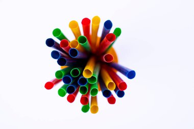 Çevre dostu veya parti temaları için renkli içecek pipetlerinin izole edilmiş bir görüntüsü, beyaz yüzeyde sarı konteynırda duran renkli pipetler grubu