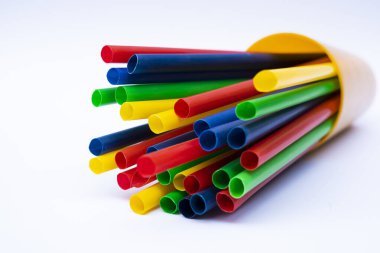 Plastik çoklu renkli içecek pipetlerinin beyaz arkaplandaki bir konteynırda yakın plan çekimi, silindirik bir fincanda plastik pipetlerin beyaz bardakta yakalandığı stüdyo fotoğrafı.