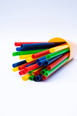 Beyaz arka planda renkli plastik pipetler yığını, düzenli bir şekilde gösterilen çeşitli içecek pipetleri, ambalaj veya yaşam tarzı görselleri için ideal.