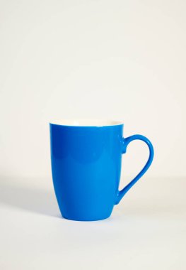  Sade beyaz bir yüzeye yerleştirilmiş modern mavi seramik bir kahve kupası. Çay fincanı, kahve fincanı