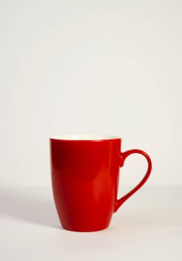 Canlı kırmızı seramik bir kupa, temiz beyaz bir arkaplanda tek başına duruyor..