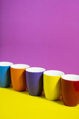 Yaz tarzı pastel bardaklar koyu sarı ve pembe arka planda üst üste dizilmiştir.