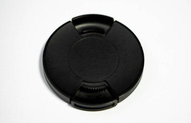Bu görüntü beyaz bir yüzeye izole edilmiş siyah bir lens kapağı içeriyor, kamera koruma aksesuarlarını göstermek için mükemmel. Temiz arka plan, fotoğrafçılar için temel bir unsur olan lens kapağının basitliği ve uygulanabilirliğine dikkat çekiyor.. 