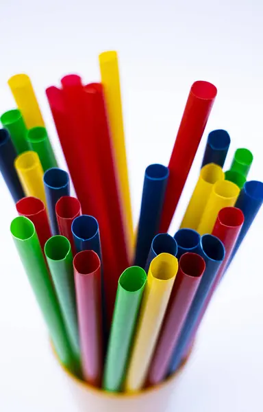 Renkli plastik pipetlerin yakın plan beyaz zemin üzerinde ayakta duran fincan