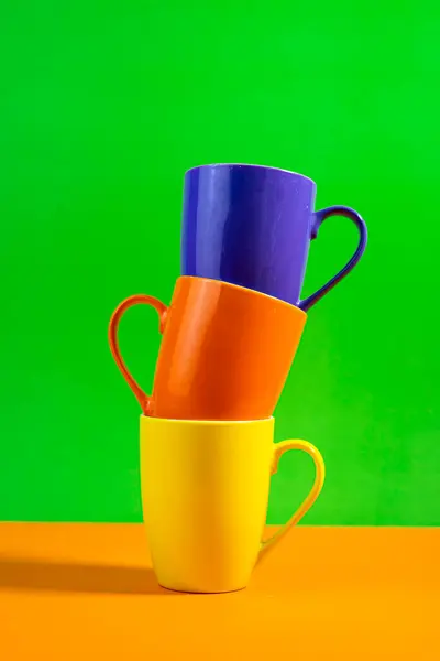 Yaşam tarzı markalaştırma veya reklam modellemeleri için mükemmel renkli içki takımı, markalaşma için yeşil ve turuncu arka planda birikmiş Kalın Çokrenkli bardaklar