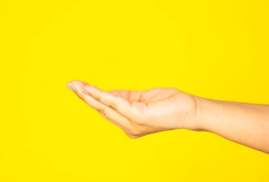 Açık bir insan elinin saf sarı bir arka plana yakın çekimi, minimalist ve temiz bir kompozisyonda kaydedildi. Ürünün sergilenebileceği yüzen veya dijital ürünler, marka ürünleri veya yaratıcı reklamlar için idealdir