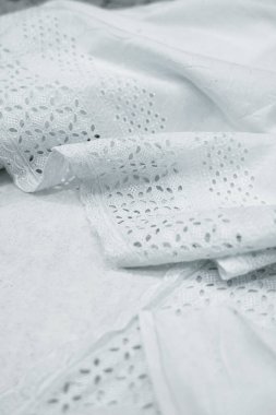 Yakın çekim beyaz göz bağı kumaşının ayrıntılı detaylarını ortaya çıkarır. Kumaş yumuşak bir şekilde örtülmüş, hassas, desenli deliklerini ve dokulu yüzeyini sergiliyor. Malzemenin hafif, havadar kalitesi vurgulandı 