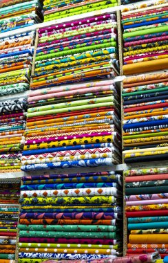 Titizlikle düzenlenmiş kumaş cıvatalarının nefes kesici bir görüntüsü, her biri eşsiz ve canlı bir desen sergiliyor. Zengin renkler ve çeşitli tasarımlar büyüleyici bir görsel duvar halısı yaratıyor, tekstil sanatının ve kültürel çeşitliliğin özünü yakalıyor..