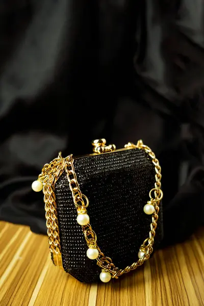 Göz kamaştırıcı bir siyah gece debriyajı. Parlak kristallerle özenle hazırlanmış. Lüks bir altın zincir ve ince inci aksanla süslenmiş. Özel durumlar için mükemmel. Bu sofistike aksesuar her kıyafete biraz cazibe katar..