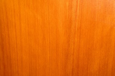 Görüntü, portakal ahşap dokusunun yakın çekimini gösteriyor. Arka plan ve ön plan, materyalin tutarlı dikey tahıl kalıbıyla dolu. Doku pürüzsüz, portakal renginin gölgesinde ince varyasyonlar var.