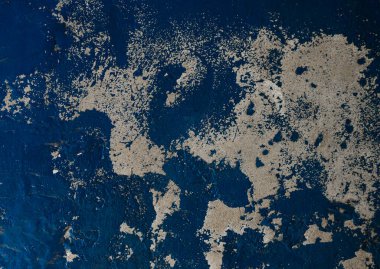 Görüntü, desenli bir yüzeyin detaylı bir yakın çekimini gösteriyor. Derin mavi bir taban yoğun şekilde benekli ve soyulmuş bej boya parçalarıyla kaplıdır. Bu da soyut ve neredeyse mermer bir etki yaratır.